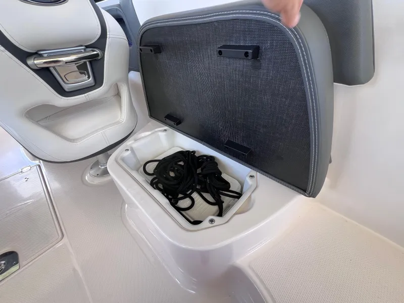 Slide: The Image of 2022 Chaparral 267 SSX OB boat storage compartment with black rope inside. - 16