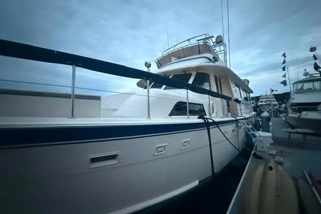 Slide: The Image of 1987 Hatteras 72 Motor Yacht docked, showcasing sleek design and spacious deck. - 2