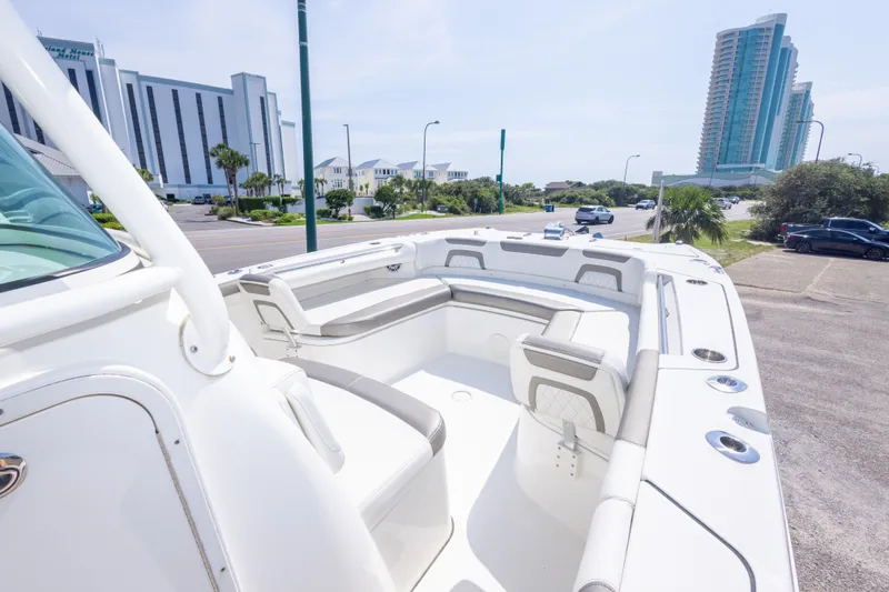 Slide: The Image of 2022 World Cat 325 CC boat with spacious seating, parked near modern buildings. - 32