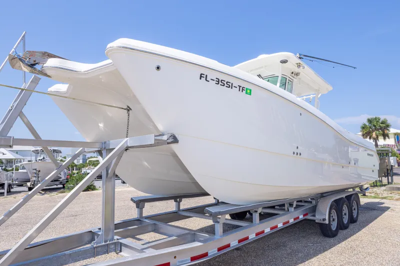 Slide: The Image of 2022 World Cat 325 CC boat on trailer, displayed outdoors under clear blue sky. - 20