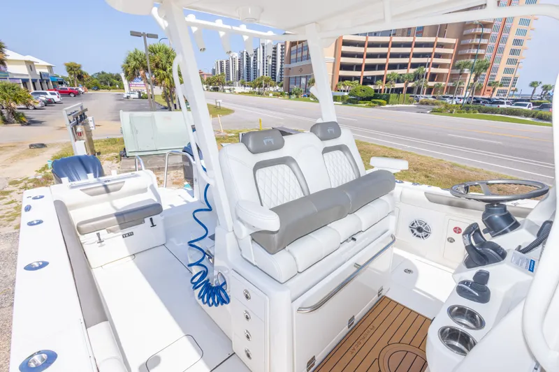 Slide: The Image of 2022 World Cat 325 CC boat interior with modern seating and steering, parked near a road. - 50