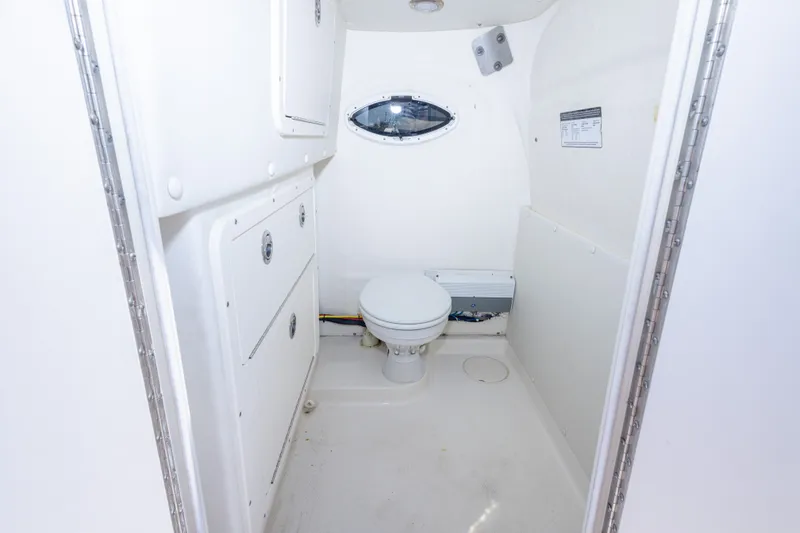 Slide: The Image of 2022 World Cat 325 CC boat interior bathroom with white fixtures and storage compartments. - 33