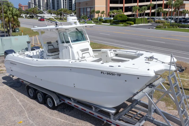 Slide: The Image of 2022 World Cat 325 CC boat on trailer, parked near a road with palm trees. - 1