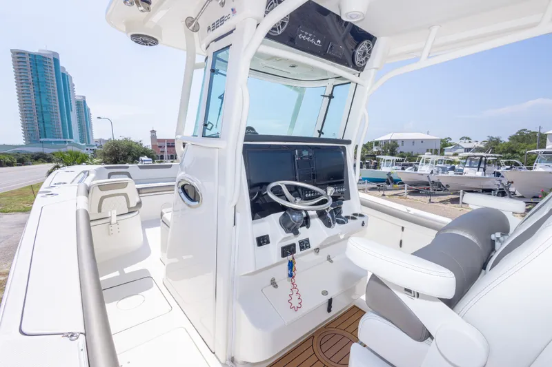 Slide: The Image of 2022 World Cat 325 CC boat cockpit with modern controls and seating, docked near buildings. - 26
