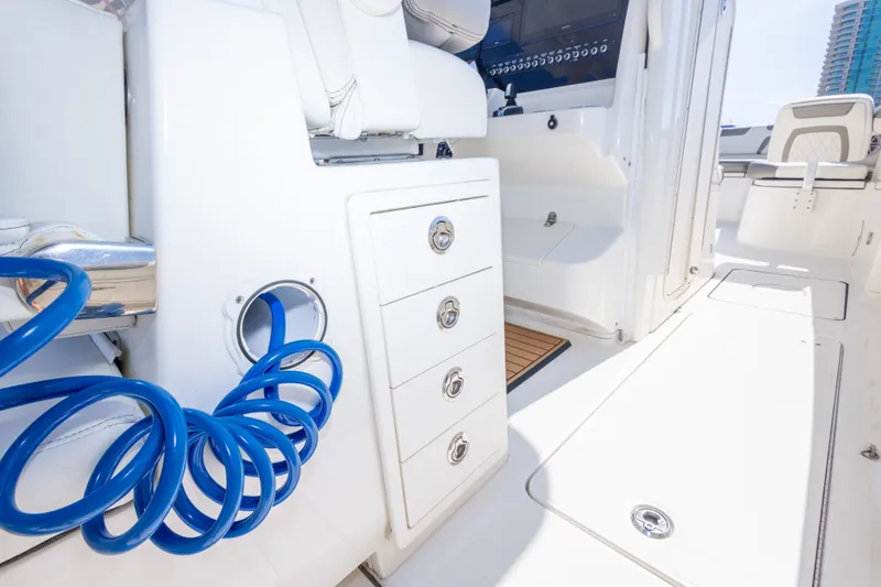 Slide: The Image of 2022 World Cat 325 CC boat interior with storage drawers and blue hose. - 57