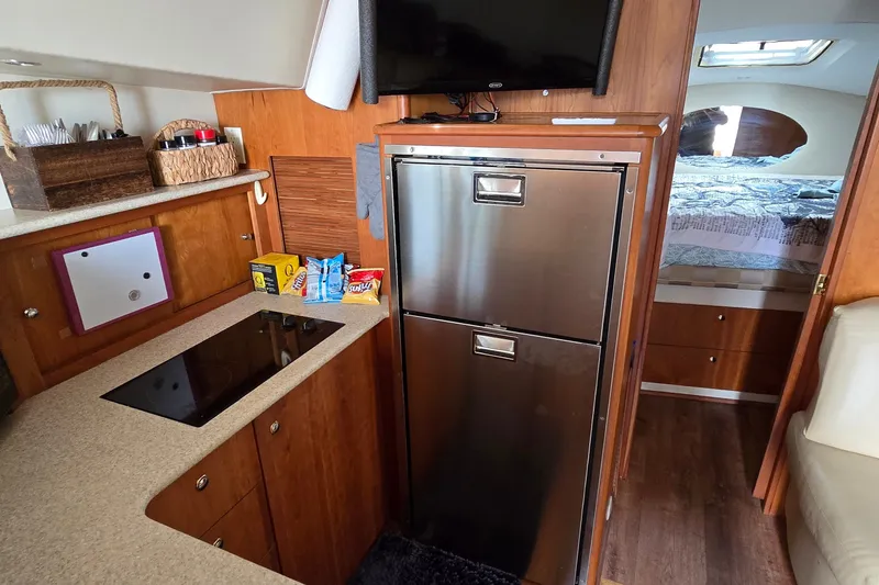 Slide: The Image of 2001 Silverton 330 Sport Bridge interior with kitchenette, fridge, and cozy sleeping area. - 23