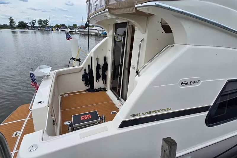 Slide: The Image of 2001 Silverton 330 Sport Bridge yacht docked at a marina, featuring a spacious deck. - 2