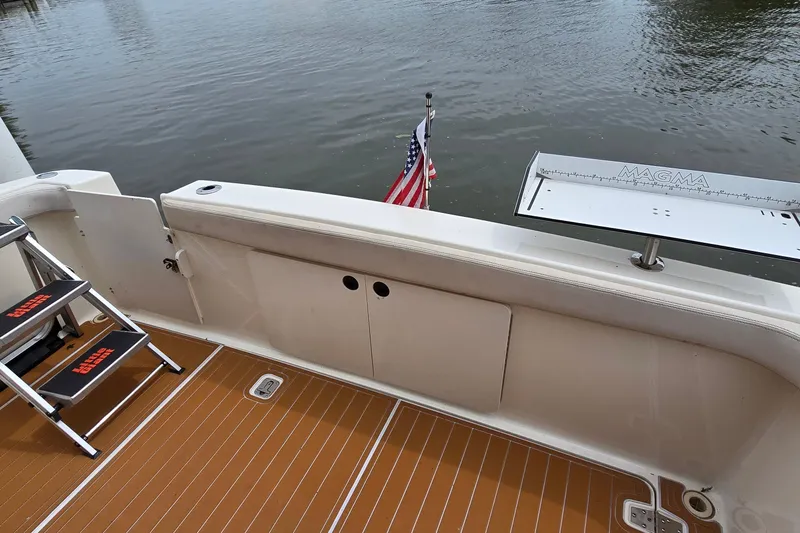 Slide: The Image of 2001 Silverton 330 Sport Bridge deck with ladder, American flag, and Magma grill. - 7