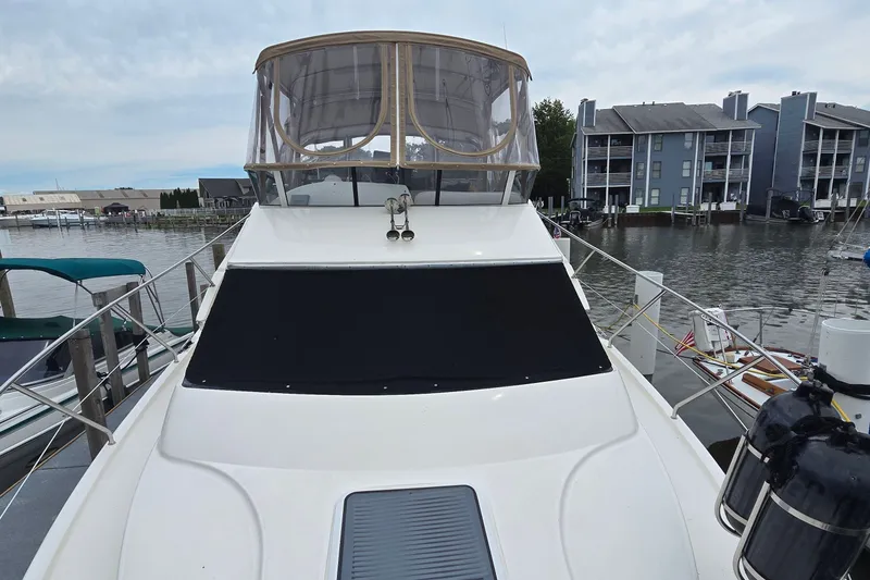 Slide: The Image of 2001 Silverton 330 Sport Bridge yacht docked at marina, featuring enclosed flybridge. - 16