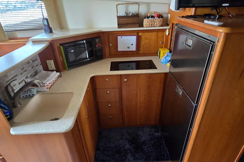 Slide: The Image of 2001 Silverton 330 Sport Bridge kitchen with sink, microwave, and fridge. - 22