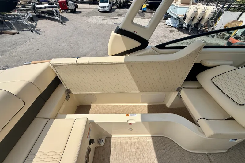 Slide: The Image of 2027 Chris-Craft Sportster 28 OB interior with beige seating and storage compartment. - 13
