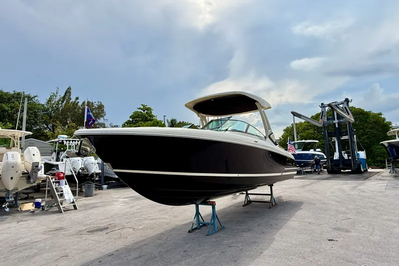 Slide: The Image of 2027 Chris-Craft Sportster 28 OB boat on stands, outdoor marina setting. - 28