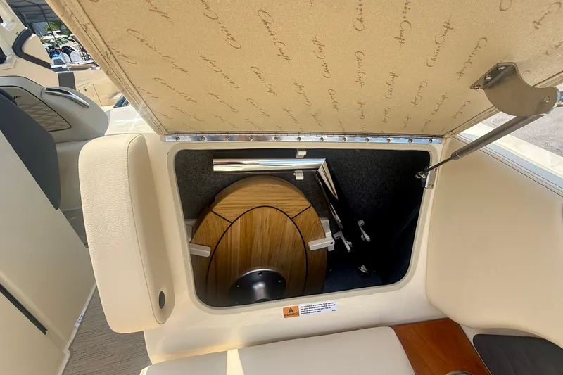 Slide: The Image of 2027 Chris-Craft Sportster 28 OB storage compartment with wooden table and seating. - 27