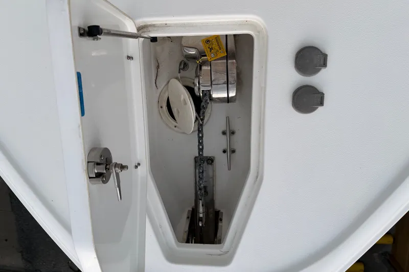 Slide: The Image of Anchor compartment of 2022 Sea Hunt Ultra 275SE boat, featuring chain and latch mechanism. - 14