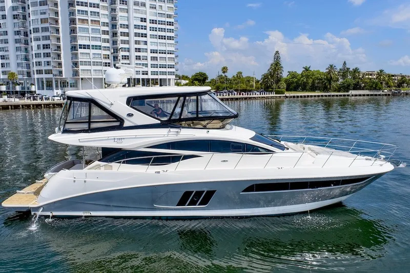 Slide: The Image of 2017 Sea Ray L590 Fly yacht cruising near waterfront buildings and lush greenery. - 11