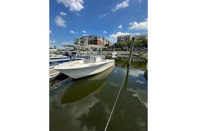 Slide: The Image of 2024 Sailfish 220 CC boat docked in a marina under a clear blue sky. - 3