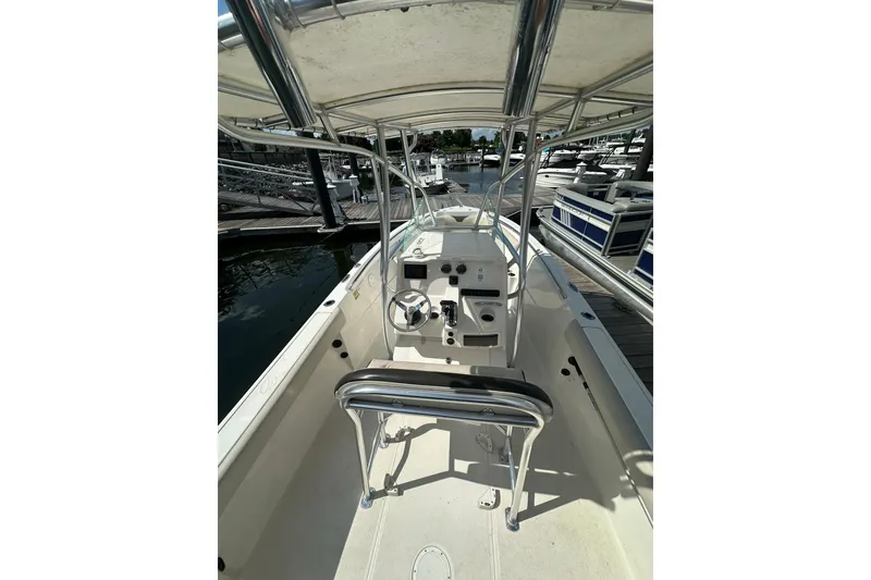 Slide: The Image of 2024 Sailfish 220 CC boat interior with steering console and seating at marina. - 8