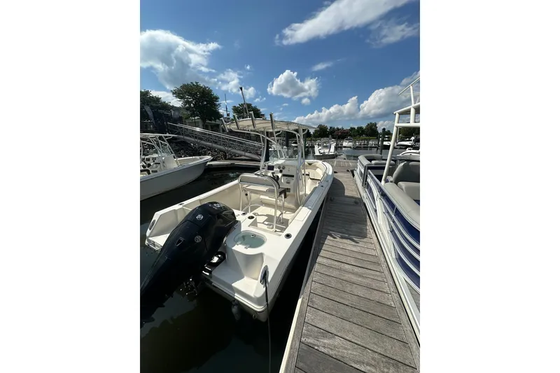 Slide: The Image of 2024 Sailfish 220 CC boat docked under a clear blue sky. - 5