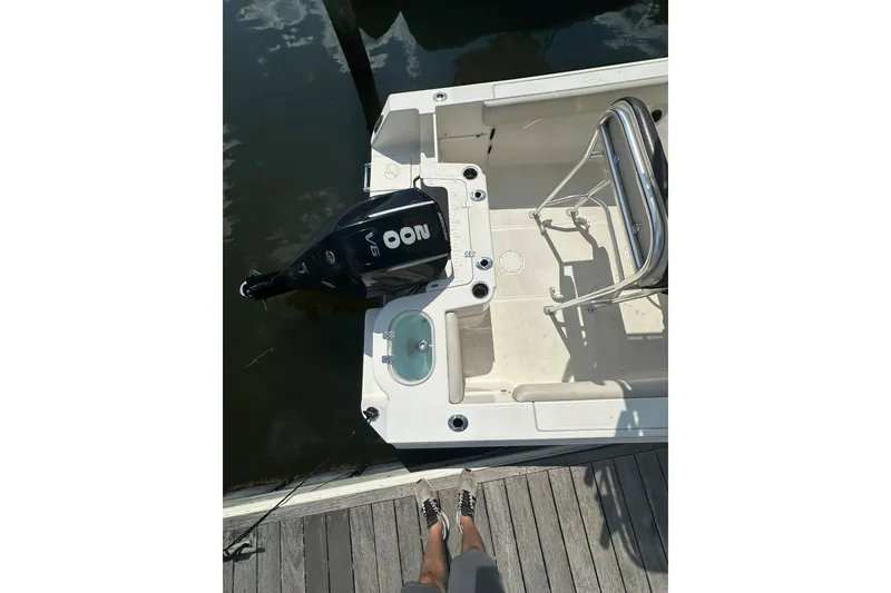 Slide: The Image of 2024 Sailfish 220 CC boat with outboard motor, docked at marina. - 7