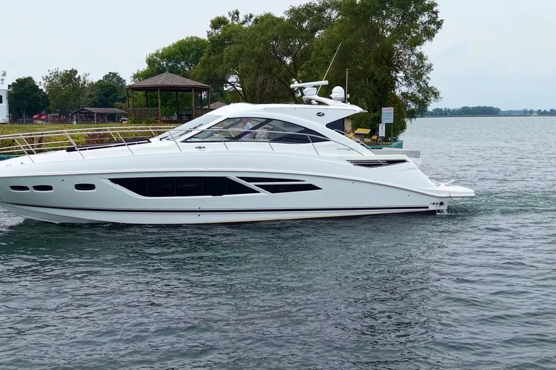 Slide: The Image of 2017 Sea Ray Sundancer 510 yacht cruising on a serene lake with lush greenery. - 5