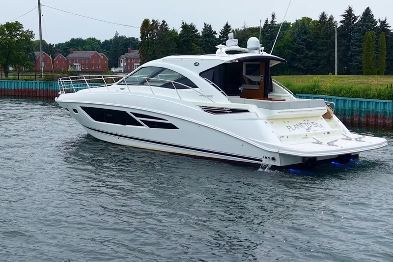 Slide: The Image of 2017 Sea Ray Sundancer 510 yacht cruising on a calm waterway near a green shoreline. - 1