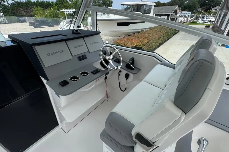 Slide: The Image of 2027 Edgewater 310SC boat cockpit with Garmin displays and plush seating. - 27
