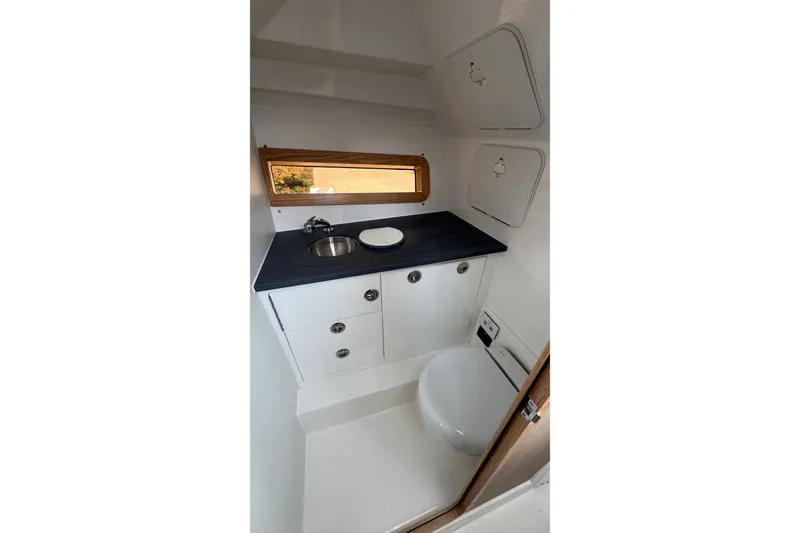 Slide: The Image of Compact bathroom in 2027 Edgewater 310SC boat with sink, toilet, and storage cabinets. - 43