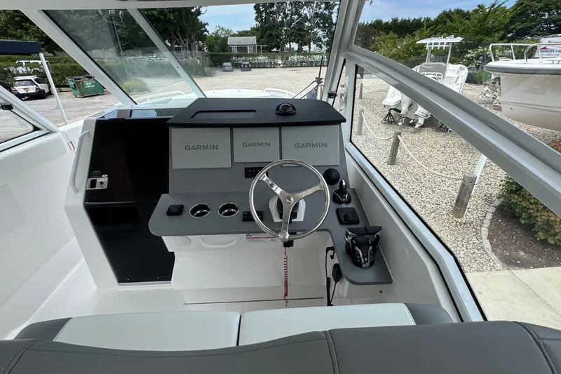 Slide: The Image of Cockpit of 2027 Edgewater 310SC boat with Garmin navigation system and steering wheel. - 28