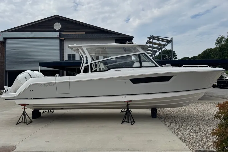The Image of 2027 Edgewater 310SC boat on stands outside a warehouse, showcasing sleek design. - 0