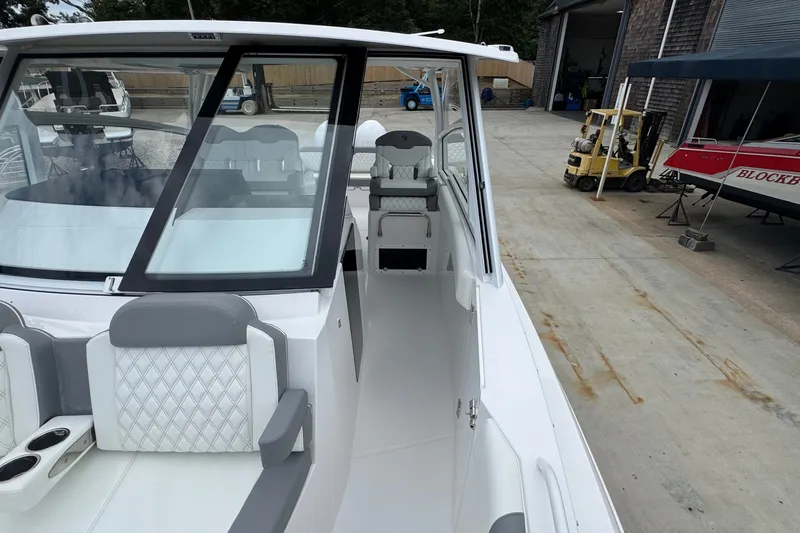 Slide: The Image of 2027 Edgewater 310SC boat interior with modern seating and sleek design in a marina setting. - 45
