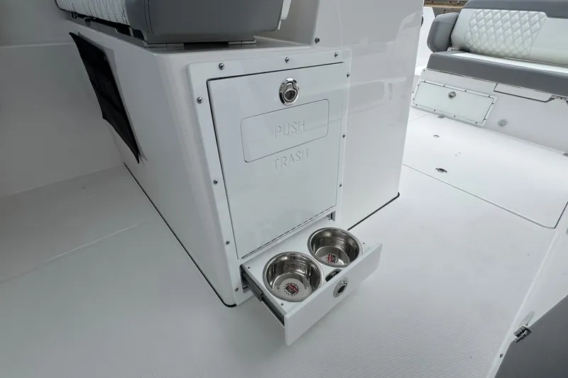 Slide: The Image of Edgewater 310SC 2027 boat interior with built-in trash compartment and pet bowls. - 36