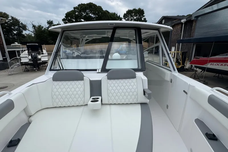 Slide: The Image of 2027 Edgewater 310SC boat interior with white and gray seating, docked outdoors. - 51