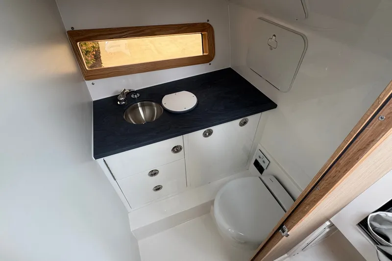 Slide: The Image of Compact bathroom in 2027 Edgewater 310SC boat with sink, toilet, and storage. - 42