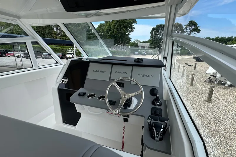 Slide: The Image of 2027 Edgewater 310SC boat helm with Garmin displays and modern steering wheel. - 29