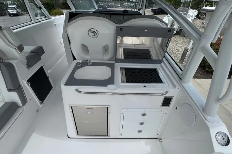 Slide: The Image of Interior of 2027 Edgewater 310SC boat featuring a compact kitchenette with sink and grill. - 20