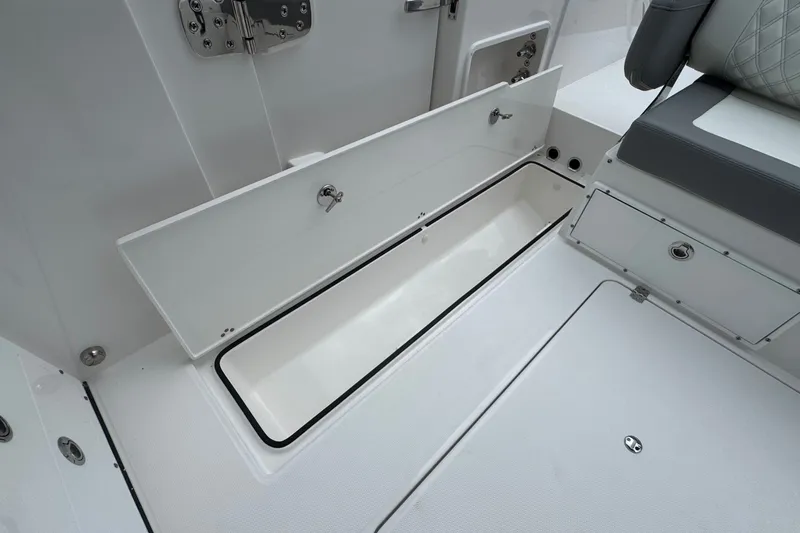 Slide: The Image of 2027 Edgewater 310SC boat interior storage compartment with open hatch and seating. - 22
