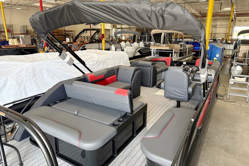 Slide: The Image of 2026 Godfrey Sweetwater 2286 SFL pontoon boat in showroom, featuring sleek gray and red seating. - 16