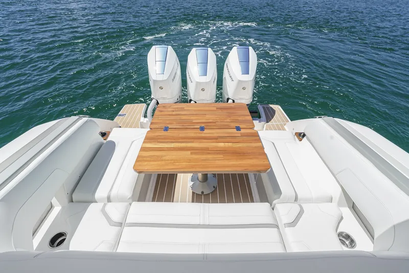 Slide: The Image of The image shows the stern of a 2024 Tiara Yachts 38 LS with three outboard engines and a wooden table. - 25