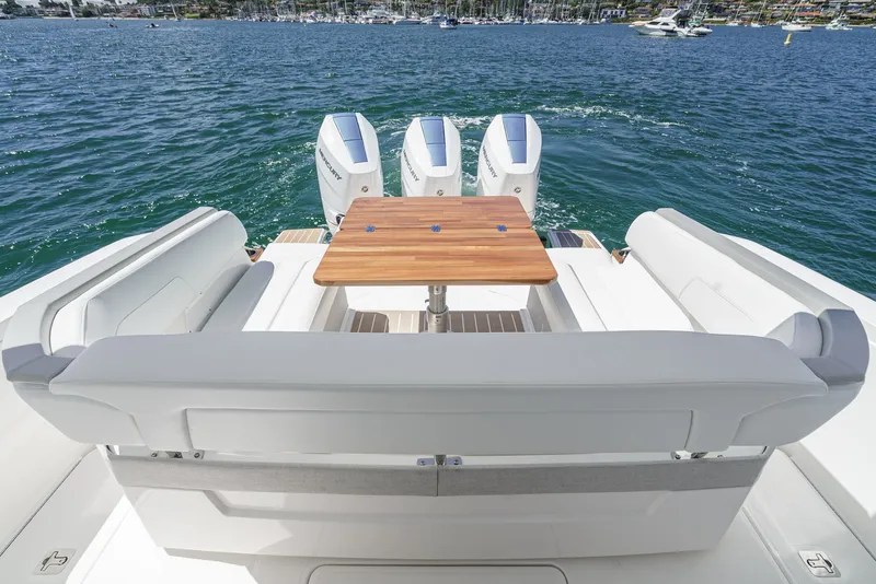 Slide: The Image of The image shows the stern of a 2024 Tiara Yachts 38 LS with three engines and a wooden table. - 24