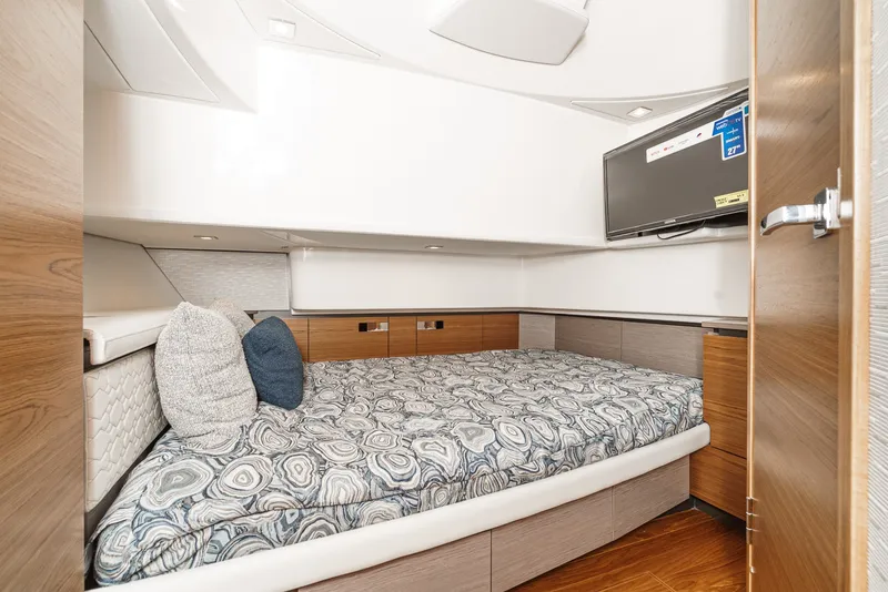Slide: The Image of The cabin of the 2024 Tiara Yachts 38 LS features a cozy bed with patterned bedding and a TV. - 48