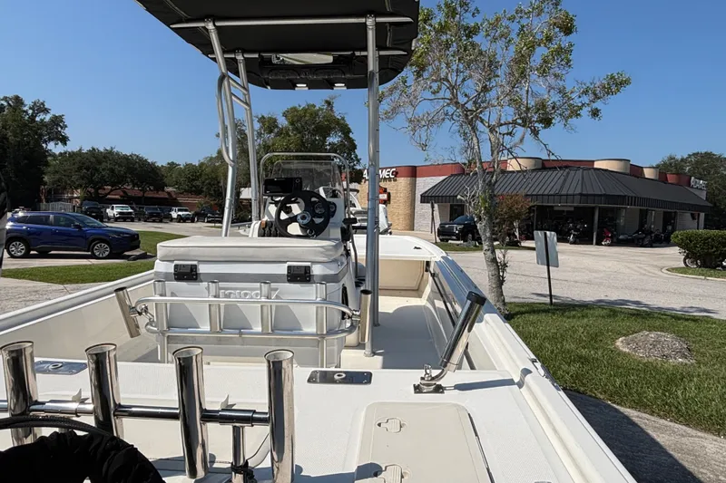 Slide: The Image of 2019 Mako Pro Skiff 19 CC boat parked near a commercial area on a sunny day. - 17