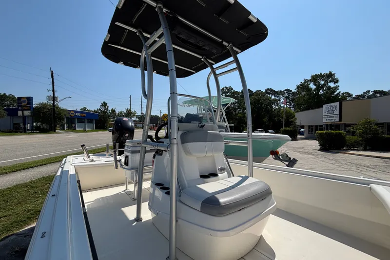 Slide: The Image of 2019 Mako Pro Skiff 19 CC boat with T-top, parked near auto parts store. - 21