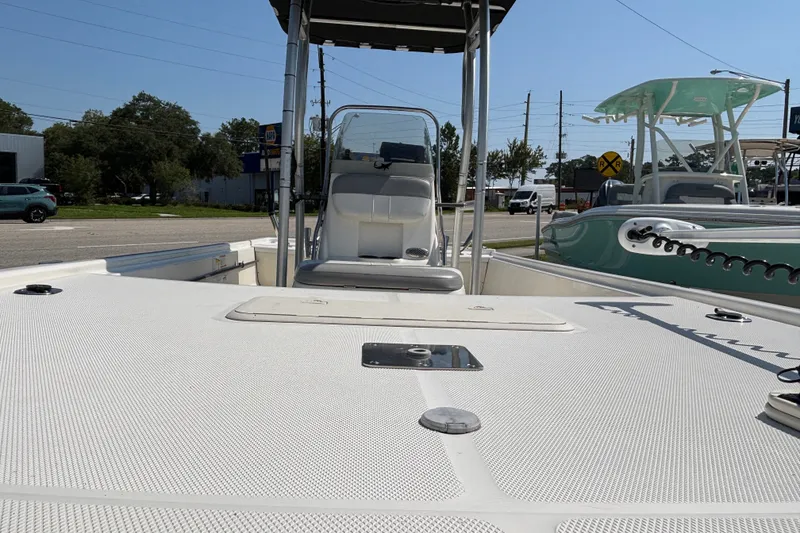 Slide: The Image of 2019 Mako Pro Skiff 19 CC boat interior with seating and console, parked outdoors. - 25