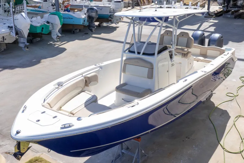 Slide: The Image of 2017 NauticStar 2602 Legacy boat with blue hull, docked in a marina. - 2