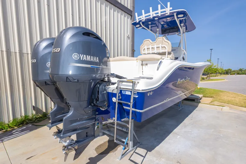 Slide: The Image of 2017 NauticStar 2602 Legacy boat with twin Yamaha 150 engines, docked outdoors. - 12