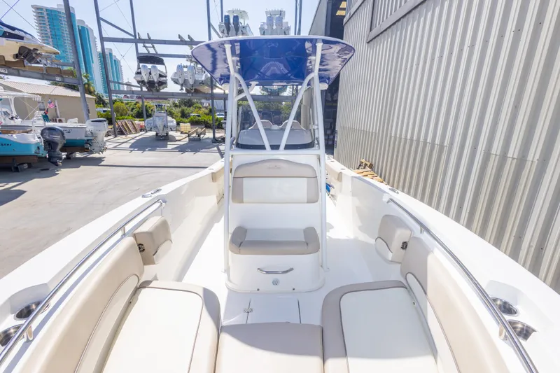 Slide: The Image of 2017 NauticStar 2602 Legacy boat interior with seating and T-top in a marina setting. - 28