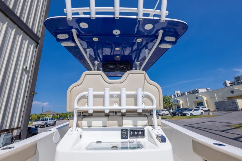 Slide: The Image of 2017 NauticStar 2602 Legacy boat with blue T-top and beige seating, parked outdoors. - 40