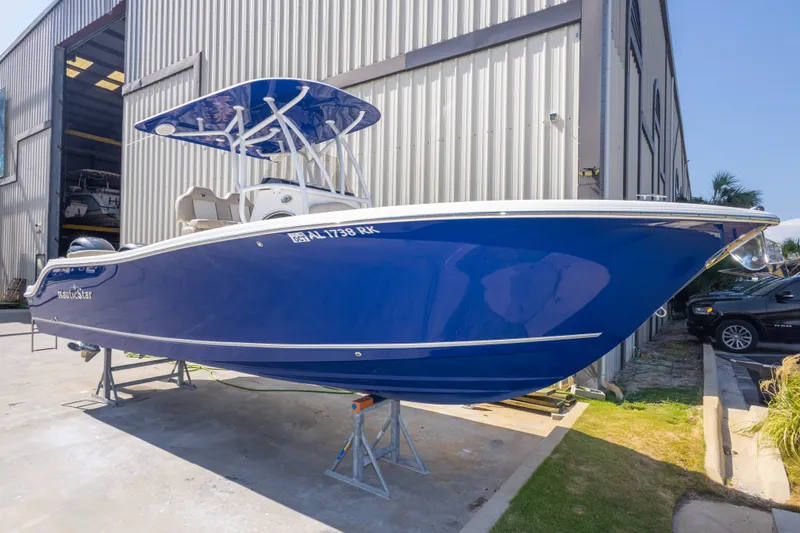 Slide: The Image of 2017 NauticStar 2602 Legacy boat in vibrant blue, docked near a warehouse. - 9