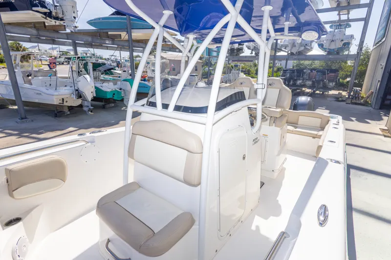 Slide: The Image of 2017 NauticStar 2602 Legacy boat interior with seating and console, docked in a marina. - 33