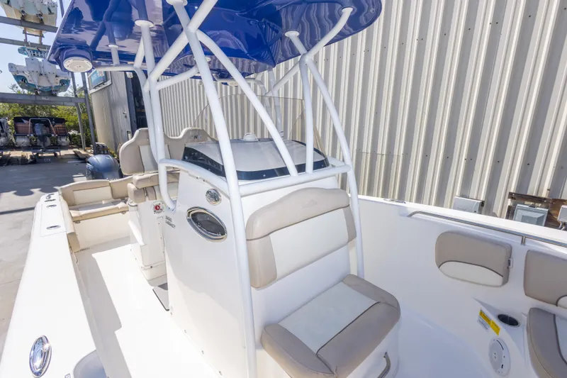 Slide: The Image of 2017 NauticStar 2602 Legacy boat with blue canopy and beige seating, docked outdoors. - 32